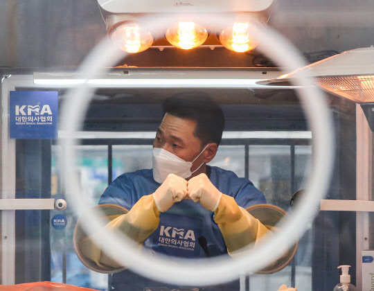 21일 오전 서울 중구 서울시청 앞 코로나19 임시 선별검사소에서 검사 담당자가 두 손을 맞대고 시민을 기다리고 있다. [연합뉴스]